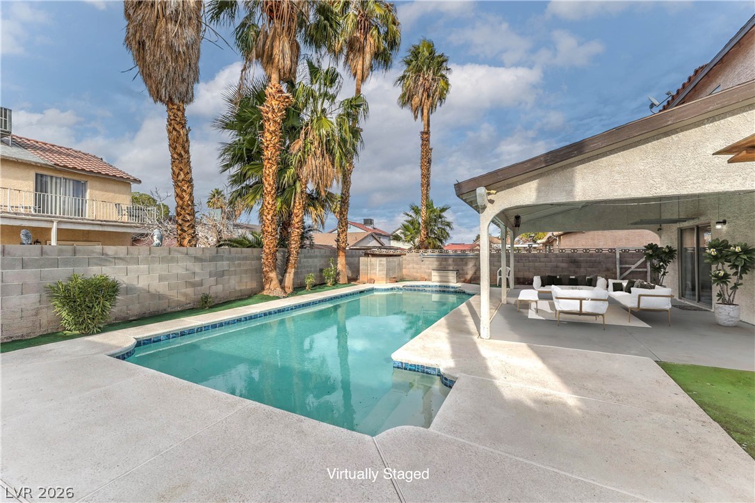 581 Carleton Drive Henderson, NV 89014 - Photo 26 of 37 A private backyard oasis features a shimmering pool, surrounded by mature palm trees and a comfortable patio for relaxation.