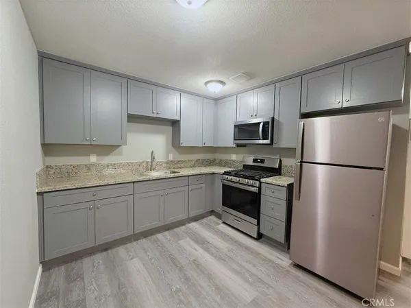 a kitchen with granite countertop stainless steel appliances a refrigerator a microwave a sink and cabinets