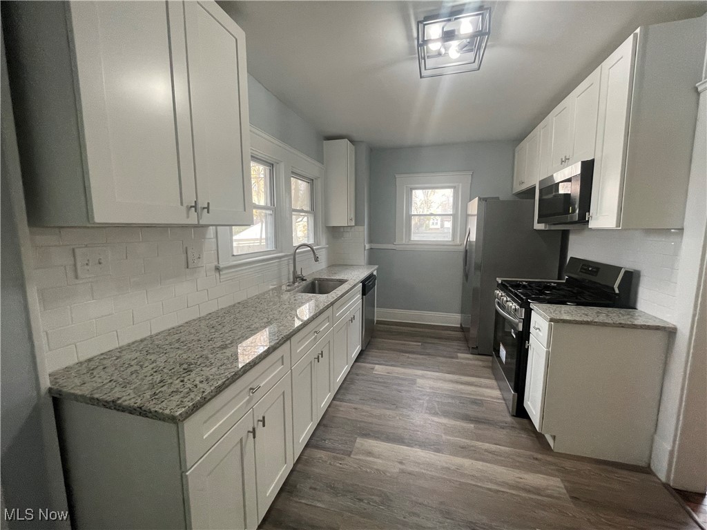 3235 Oak Road Cleveland, OH 44118 - Photo 11 of 47 Kitchen featuring stainless steel appliances, tasteful backsplash, light stone countertops, dark wood-type flooring, and white cabinets