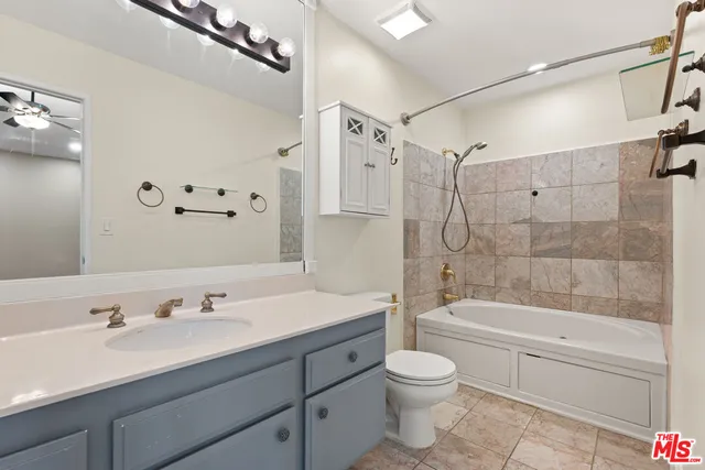 a bathroom with a granite countertop sink a toilet and a bathtub