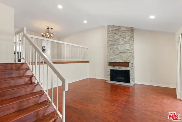 a view of an empty room with wooden floor and a fireplace