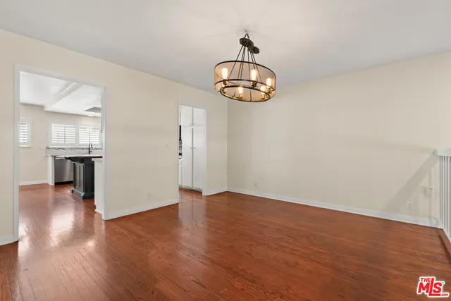 a view of an empty room with wooden floor and chandelier