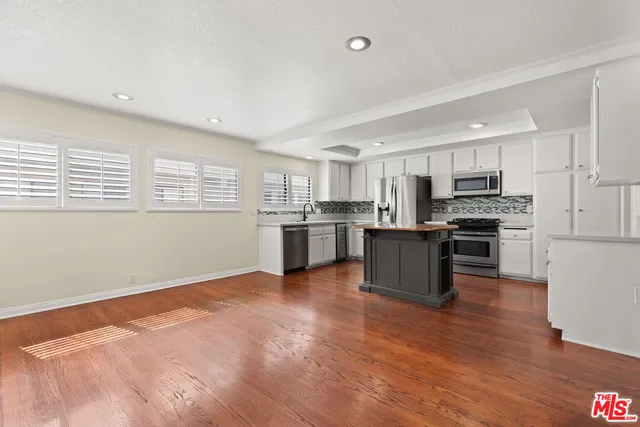 a kitchen with stainless steel appliances granite countertop a stove top oven a sink and dishwasher with wooden floor