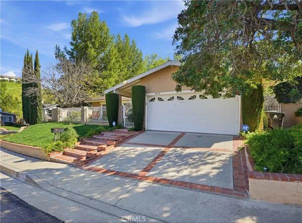 a view of a house with a yard and large tree