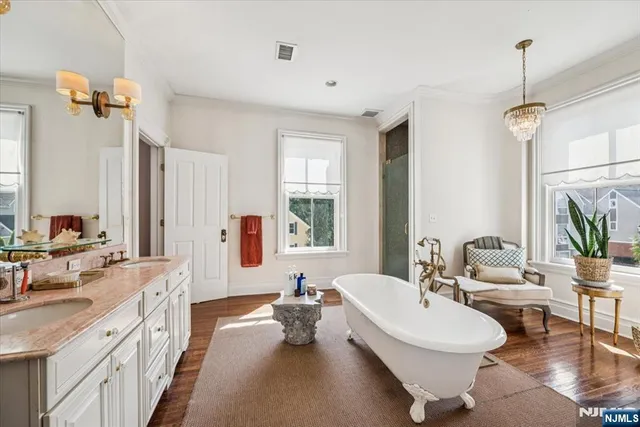 a spacious bathroom with a double vanity sink a mirror a bathtub and a window