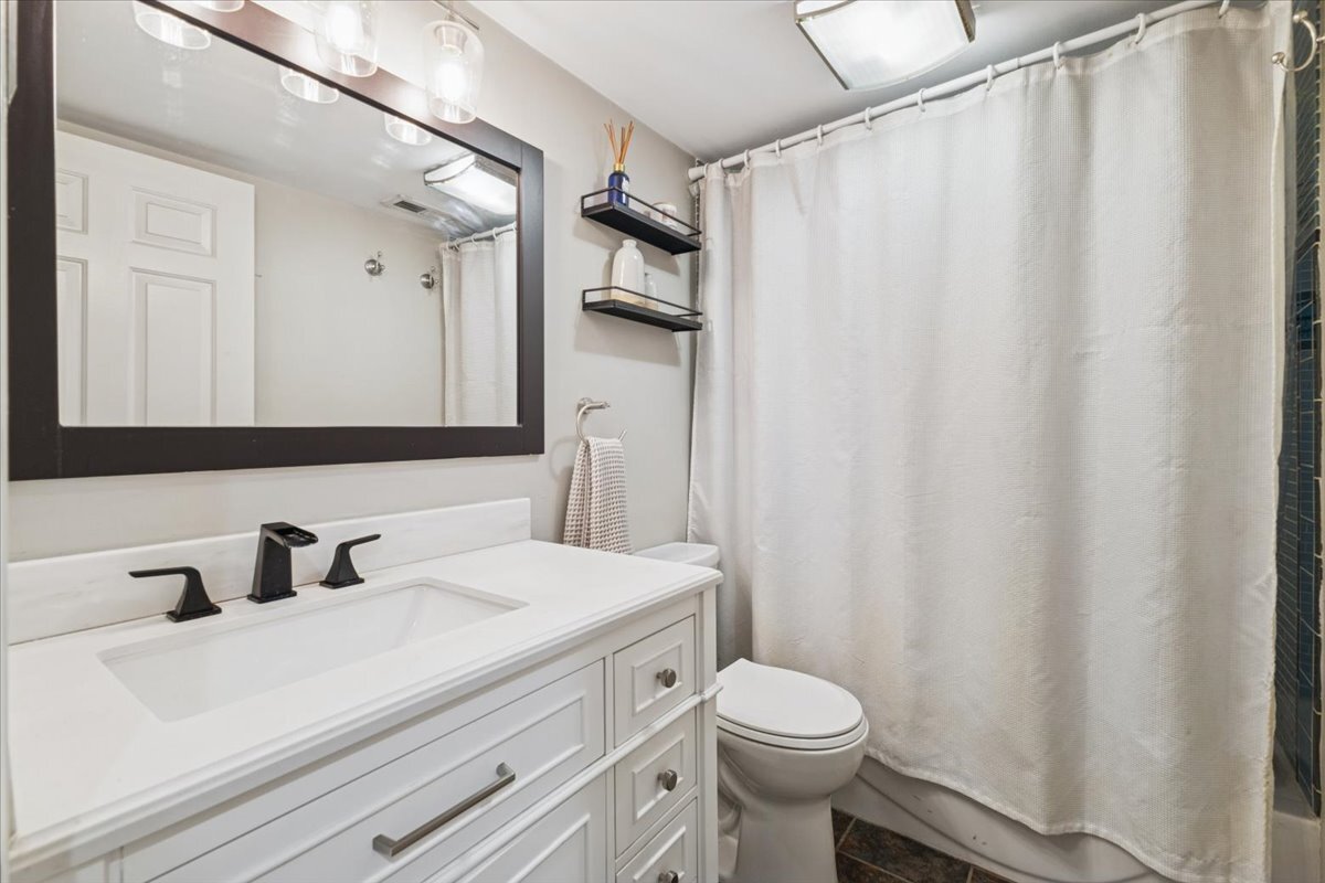 1111 North Honore Street, Unit 1 Chicago, IL 60622 - Photo 11 of 16 a bathroom with a sink a toilet a mirror and shower curtain