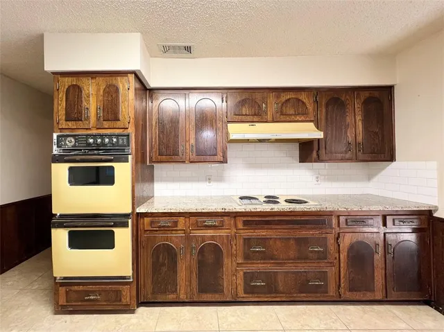 a large kitchen with stainless steel appliances granite countertop a stove a sink and a microwave