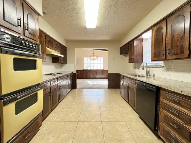 a large kitchen with stainless steel appliances granite countertop a refrigerator and a stove top oven