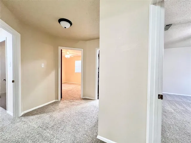 an empty room with a chandelier fan and windows