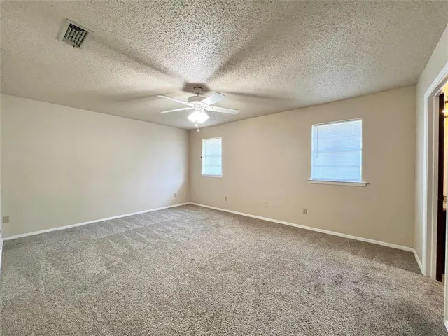an empty room with fan and windows