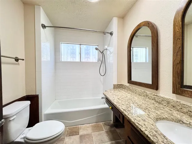 a bathroom with a granite countertop sink a mirror and a shower