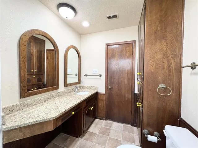 a bathroom with a granite countertop sink a toilet and shower