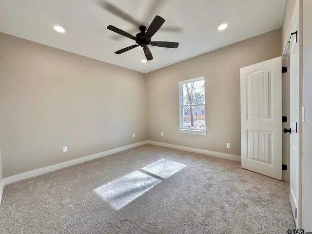 a view of a livingroom with a ceiling fan & windows
