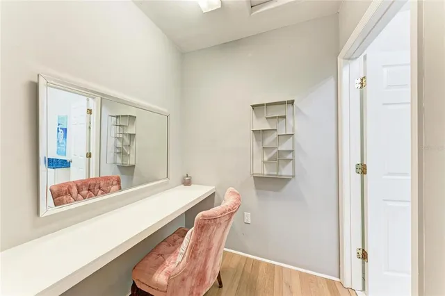 a view of a hallway to room with wooden floor and book shelf