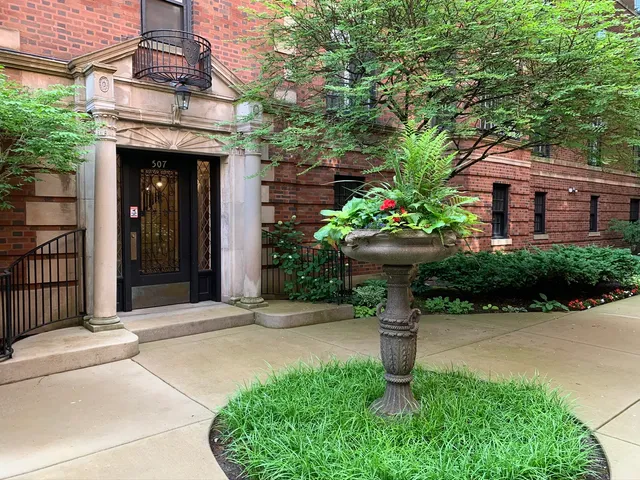 a view of a house with potted plants and a fountain