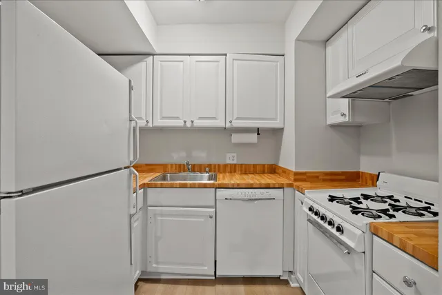a kitchen with granite countertop a stove and white cabinets