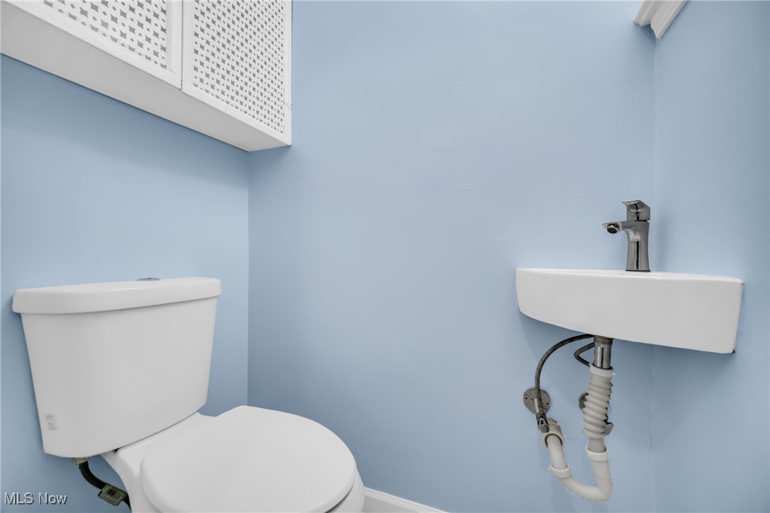 1605 Laclede Road Cleveland, OH 44121 - Photo 19 of 40 Half bath with toilet, a sink, and baseboards