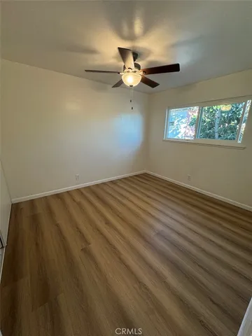 an empty room with wooden floor fan and windows