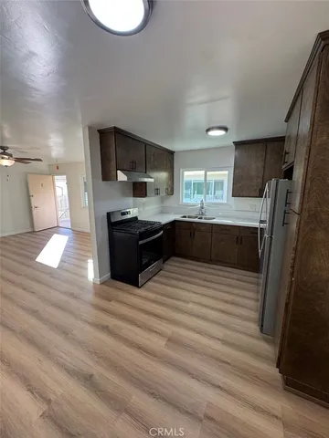 a large kitchen with stainless steel appliances a large counter top a stove a sink and a refrigerator