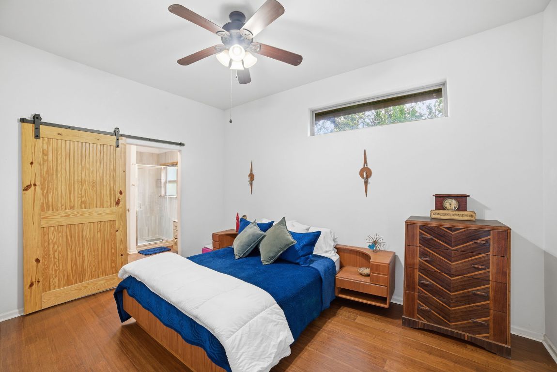 5704 Roundup Street Leander, TX 78645 - Photo 12 of 29 Bedroom with wood finished floors, ceiling fan, a barn door, and ensuite bath