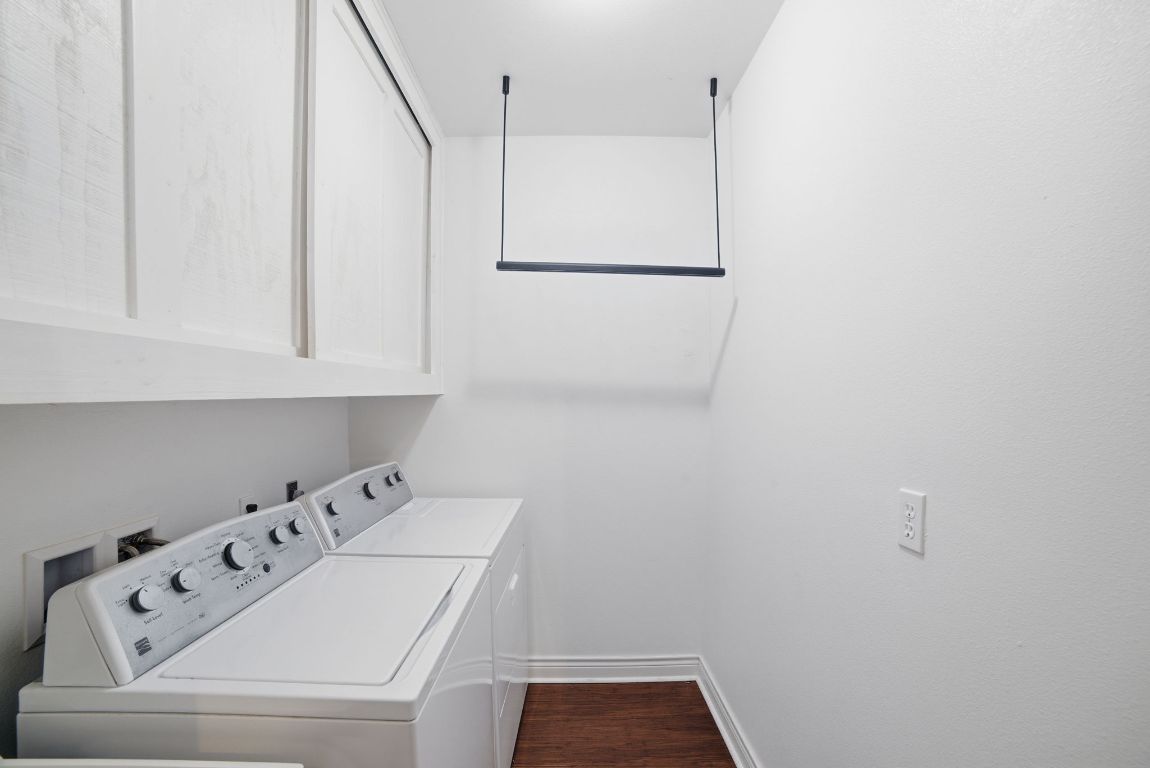 5704 Roundup Street Leander, TX 78645 - Photo 23 of 29 Laundry area with washer and dryer, dark wood-style floors, and cabinet space