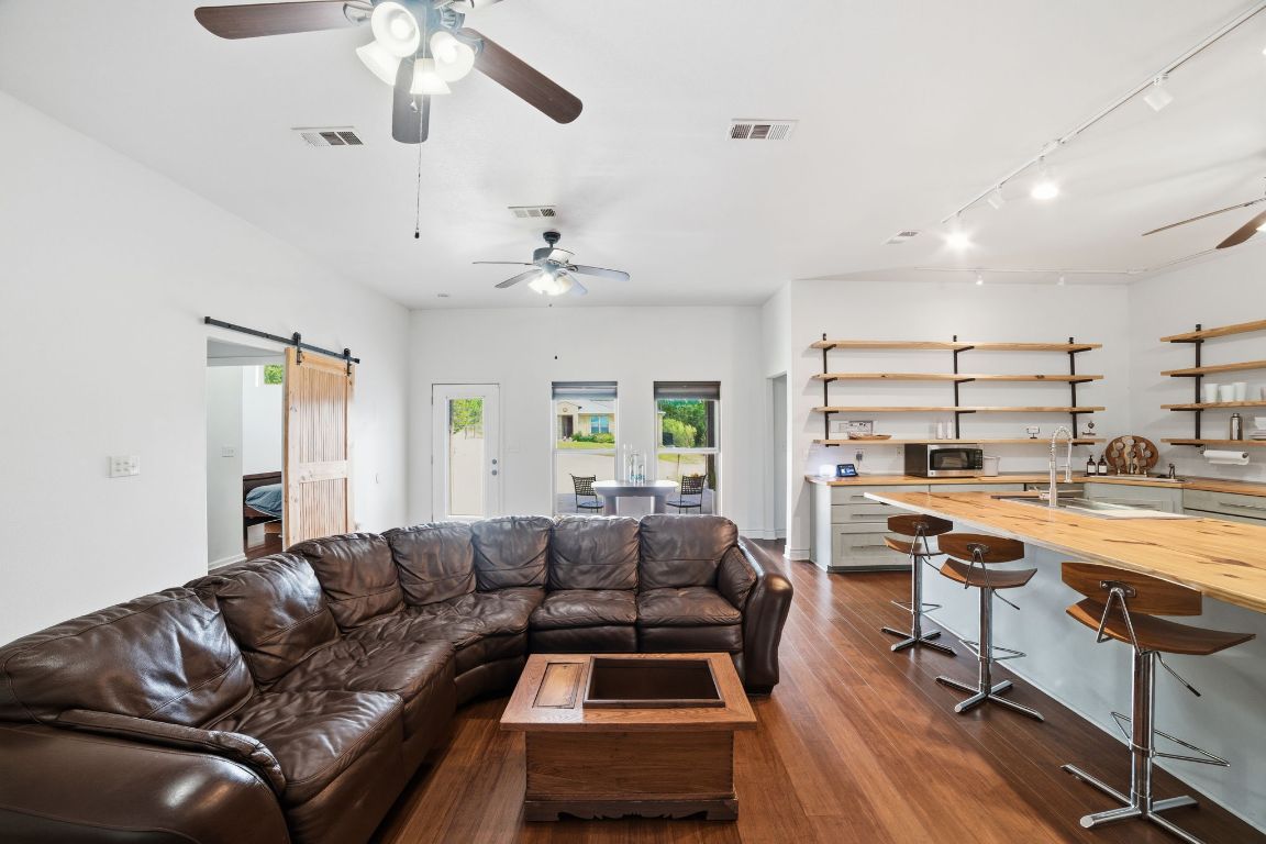 5704 Roundup Street Leander, TX 78645 - Photo 6 of 29 Living area featuring a ceiling fan, a barn door, rail lighting, and dark wood-style floors