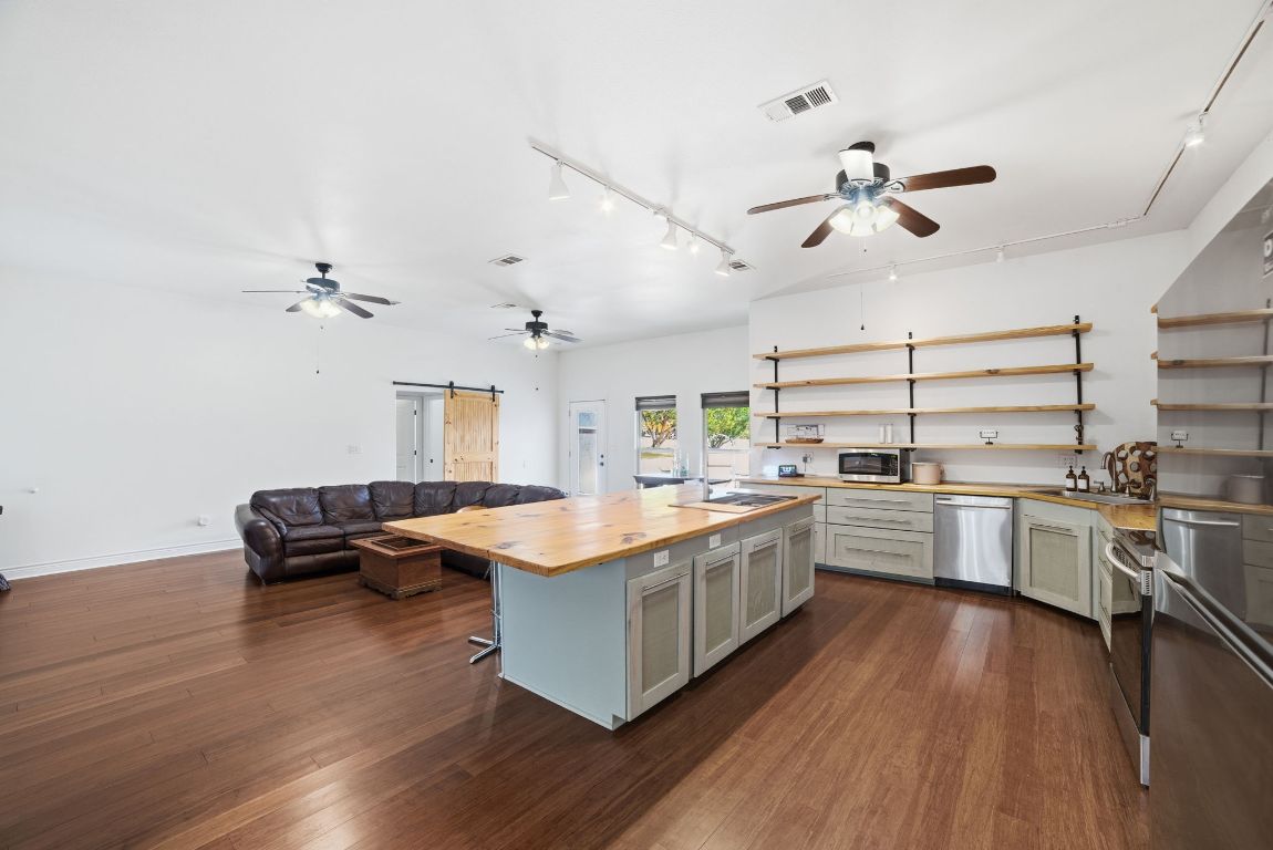 5704 Roundup Street Leander, TX 78645 - Photo 8 of 29 Kitchen with a barn door, open shelves, butcher block countertops, rail lighting, and a ceiling fan