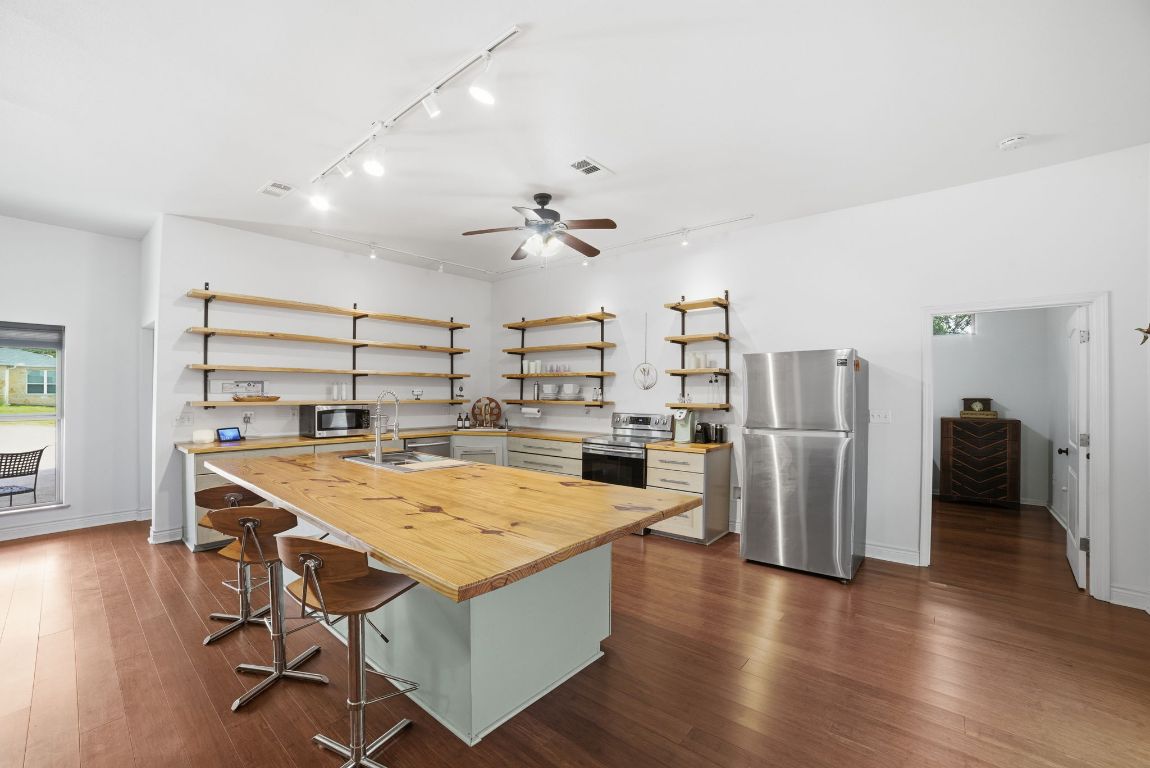 5704 Roundup Street Leander, TX 78645 - Photo 10 of 29 Kitchen featuring butcher block counters, open shelves, rail lighting, and stainless steel appliances
