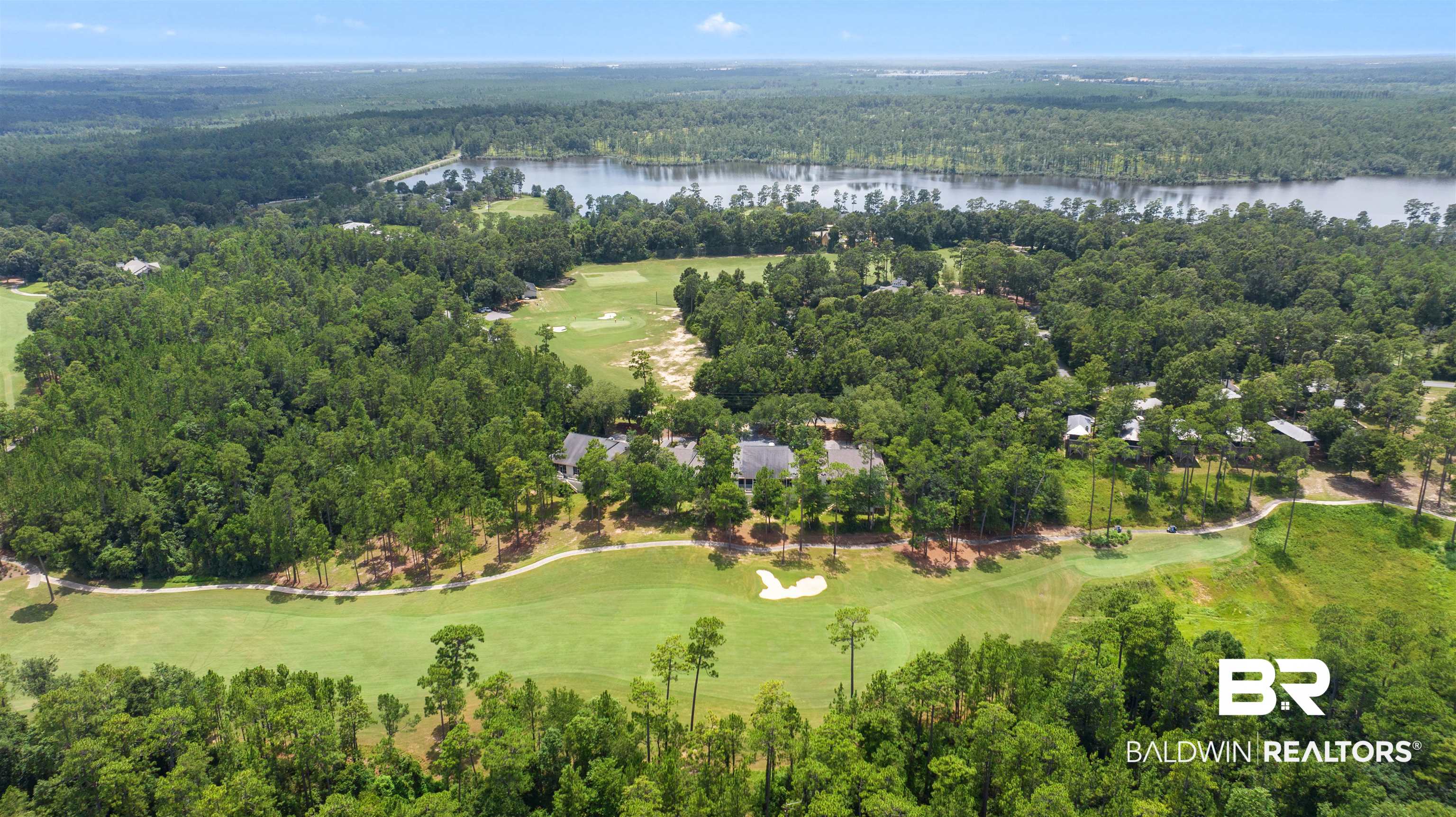 32700 Steelwood Ridge Road, Unit D Loxley, AL 36551 - Photo 40 of 41 Aerial perspective showcasing a residential community nestled within a golf course landscape, featuring mature trees, manicured greens, and a water body in the background