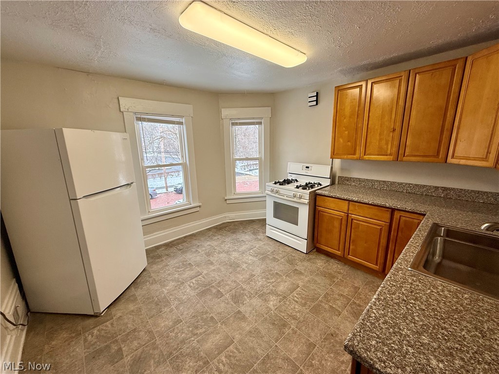 39 North Balch Street Akron, OH 44303 - Photo 9 of 19 Kitchen featuring white appliances, wood finish cabinets, a textured ceiling, dark stone countertops, and stone finish floors