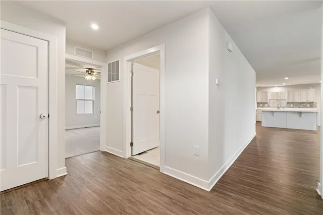 a view of a hallway with wooden floor and a kitchen