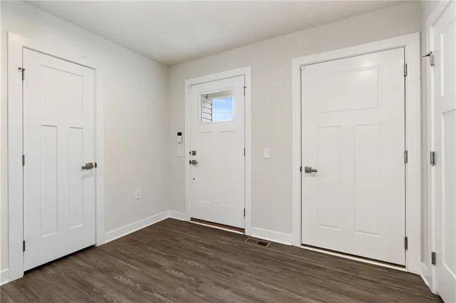a view of an empty room with wooden floor and closet