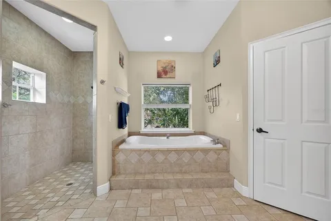 a spacious bathroom with a granite countertop sink a mirror a shower and a bathtub