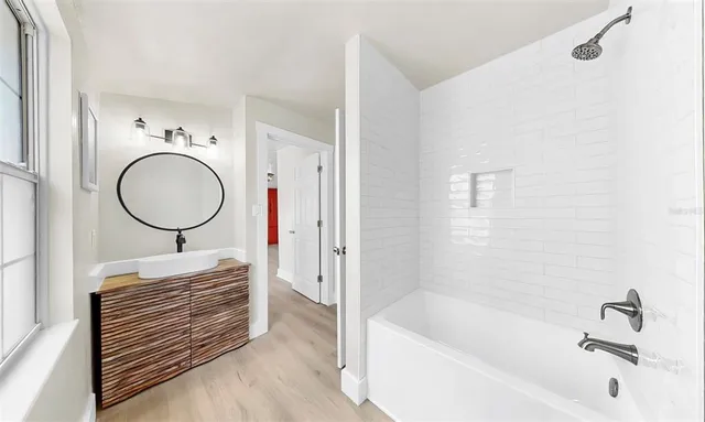 a bathroom with a bathtub a mirror and a shower