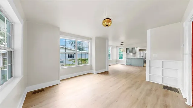 a view of an empty room with a window and wooden floor