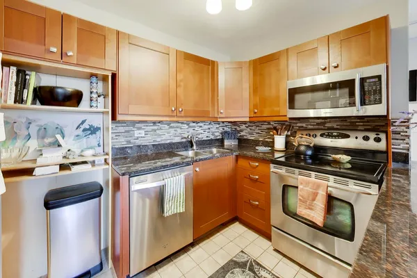 a kitchen with stainless steel appliances granite countertop a stove top oven a sink dishwasher and cabinets with wooden floor