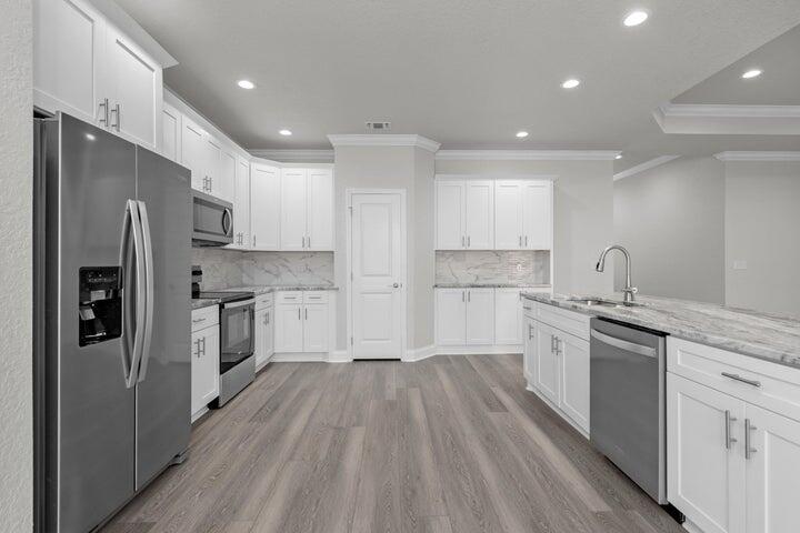 709 Northwest Lovejoy Road Fort Walton Beach, FL 32548 - Photo 3 of 4 a kitchen with white cabinets and stainless steel appliances