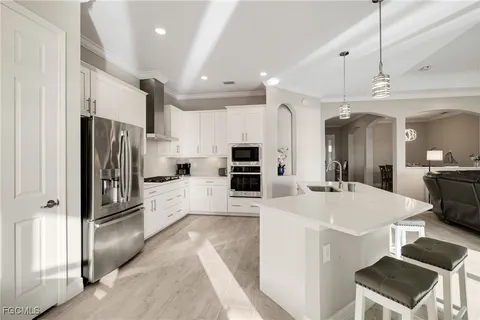 a large kitchen with kitchen island a refrigerator a stove a sink dishwasher a dining table and chairs with wooden floor