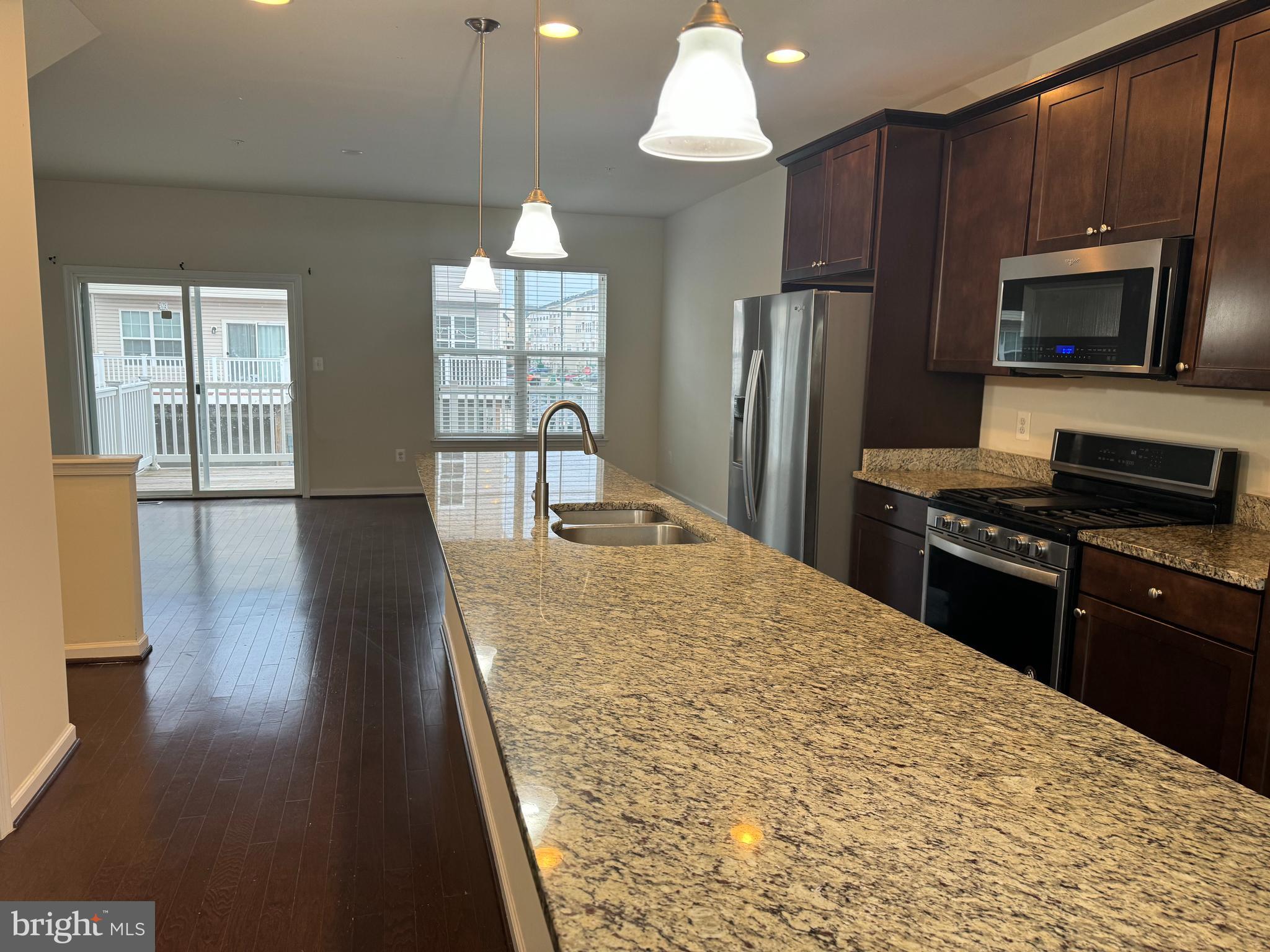 6229 Posey Street Frederick, MD 21703 - Photo 3 of 3 a kitchen with granite countertop wooden floors a refrigerator and a stove top oven