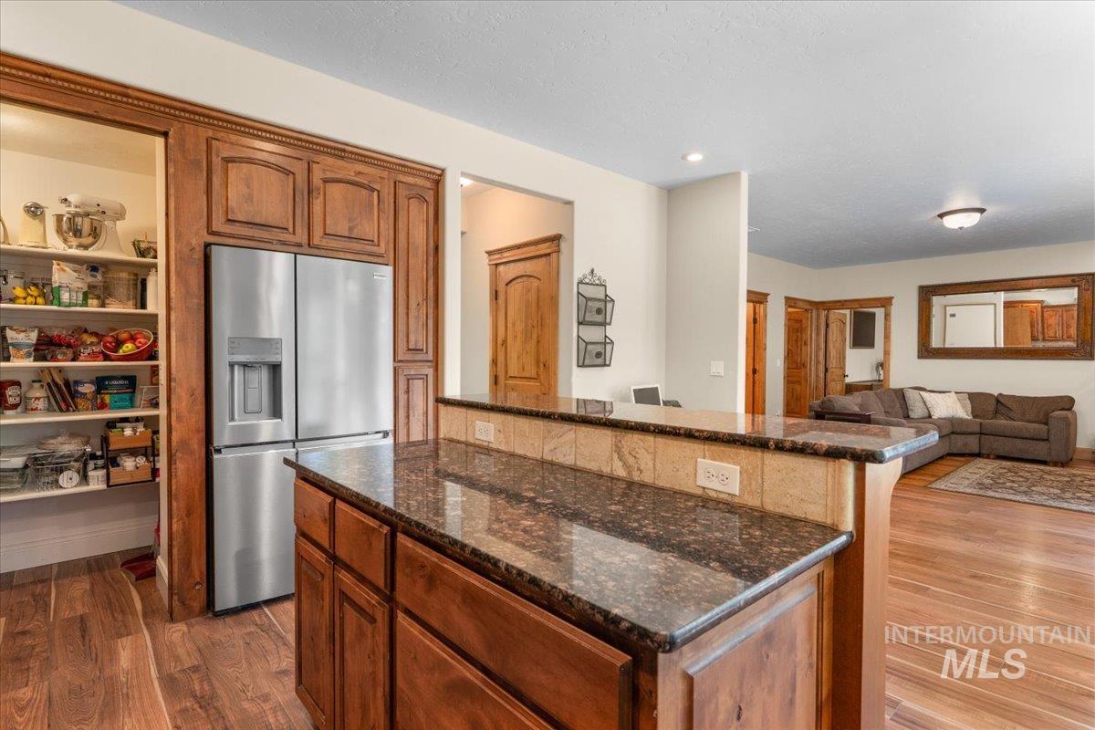 4154 North Tipton Avenue Meridian, ID 83646 - Photo 14 of 50 Kitchen featuring wood-finish flooring, wood cabinetry with crown molding, a stainless steel refrigerator, and a pantry with built-in shelving