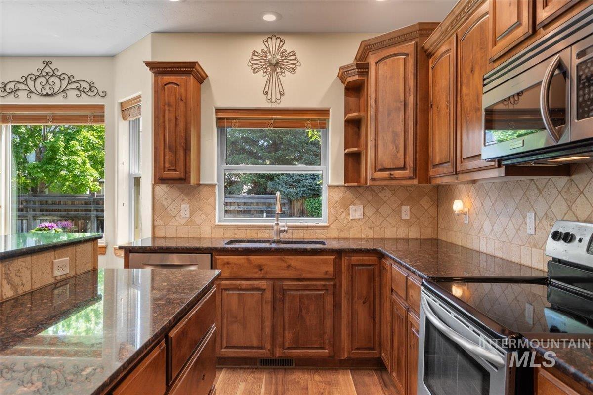 4154 North Tipton Avenue Meridian, ID 83646 - Photo 15 of 50 Kitchen featuring wood cabinetry, dark countertops, a patterned tile backsplash, stainless steel appliances, and recessed lighting