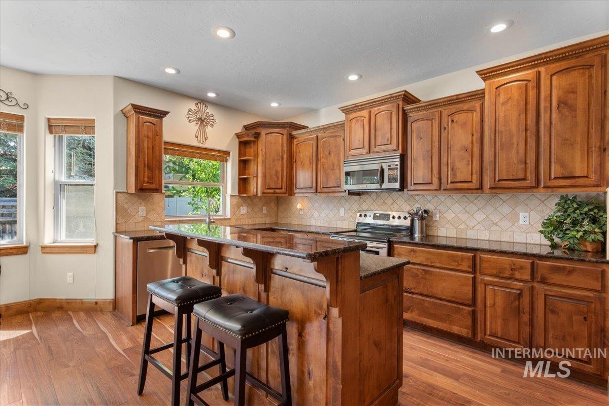 4154 North Tipton Avenue Meridian, ID 83646 - Photo 16 of 50 Kitchen featuring abundant wood cabinetry, granite countertops, stainless steel appliances, and a central island with bar seating