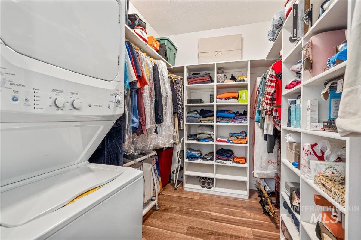 4154 North Tipton Avenue Meridian, ID 83646 - Photo 28 of 50 Organized closet space featuring a stacked washer and dryer, wood-finish flooring, and extensive built-in shelving units for storage
