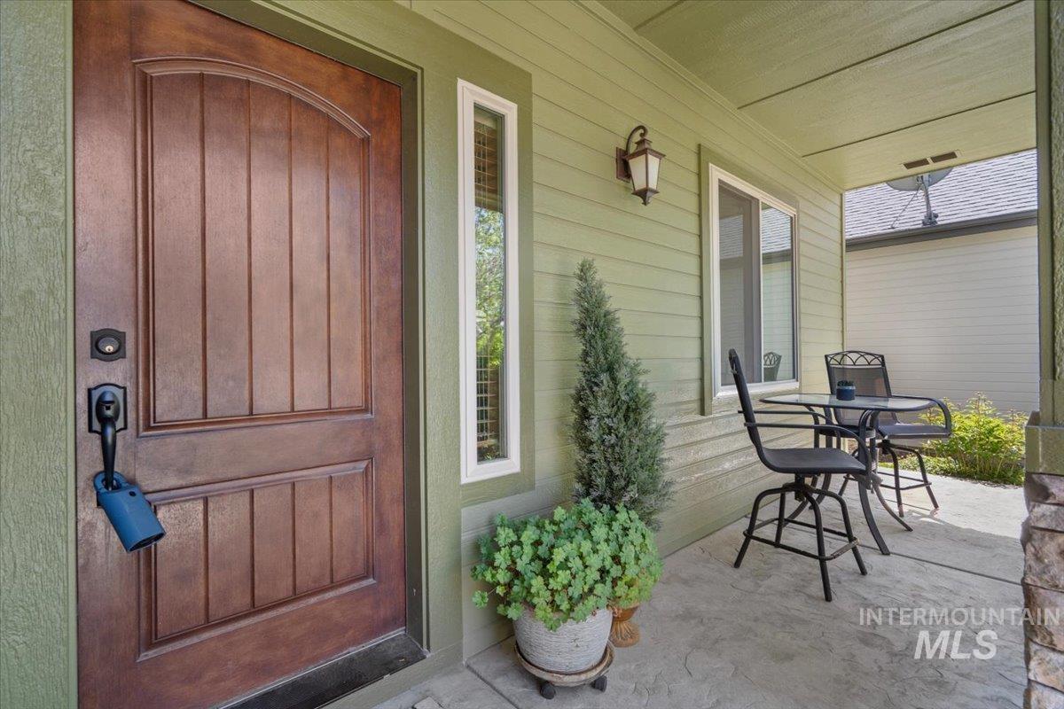 4154 North Tipton Avenue Meridian, ID 83646 - Photo 3 of 50 Inviting covered front porch with a paneled wood-finish entry door, a sidelight window, and a wall-mounted sconce