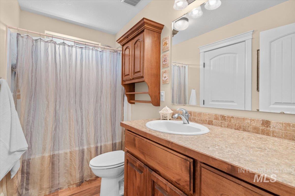 4154 North Tipton Avenue Meridian, ID 83646 - Photo 33 of 50 Bathroom featuring a single vanity with an integrated sink, wood cabinetry, and a neutral-toned countertop