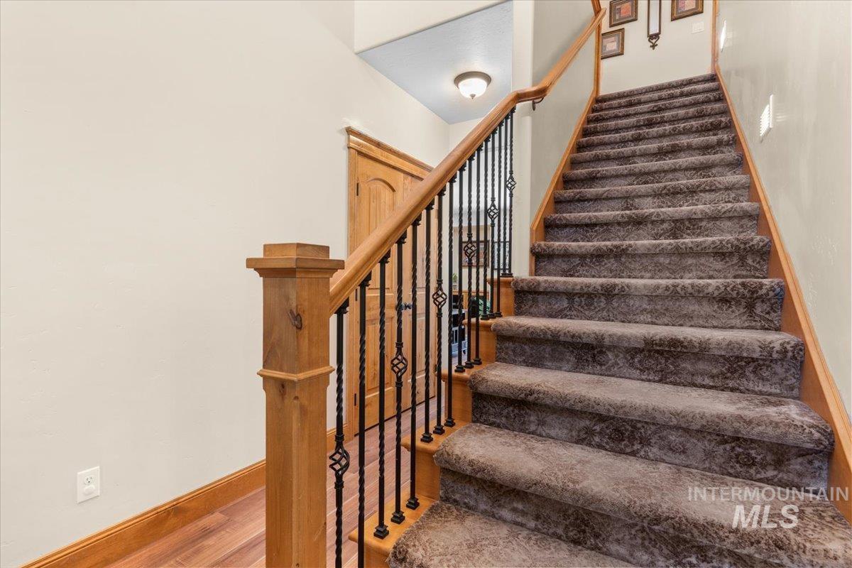 4154 North Tipton Avenue Meridian, ID 83646 - Photo 4 of 50 Staircase featuring wood newel post and handrail, wrought iron balusters, and patterned carpeted treads