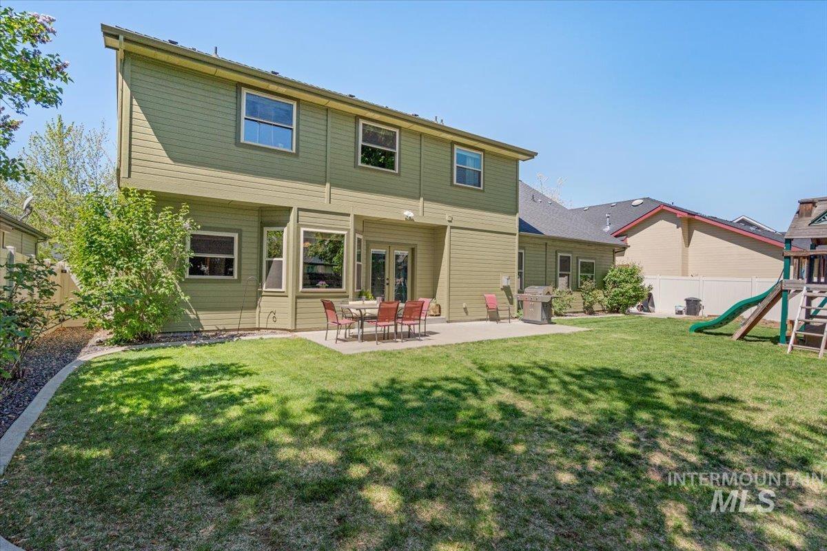 4154 North Tipton Avenue Meridian, ID 83646 - Photo 46 of 50 Expansive rear yard featuring a manicured lawn, concrete patio, mature landscaping, and multi-pane windows