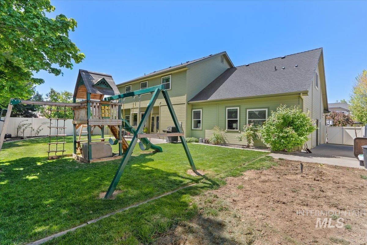 4154 North Tipton Avenue Meridian, ID 83646 - Photo 48 of 50 Expansive backyard featuring a manicured lawn, a multi-level playset with swings, and mature trees