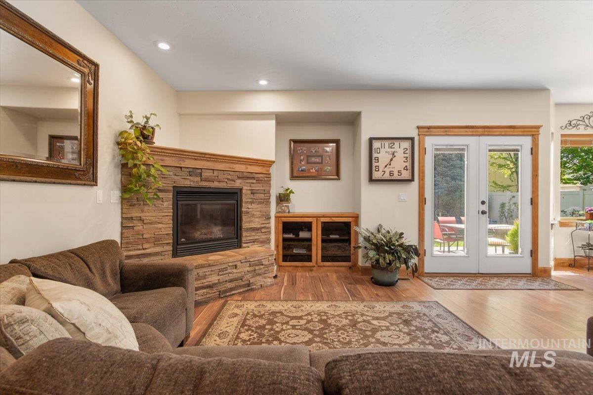 4154 North Tipton Avenue Meridian, ID 83646 - Photo 7 of 50 Living space featuring a stone-clad fireplace with a wood mantel, recessed lighting, wood-finish flooring, and French patio doors with wood trim