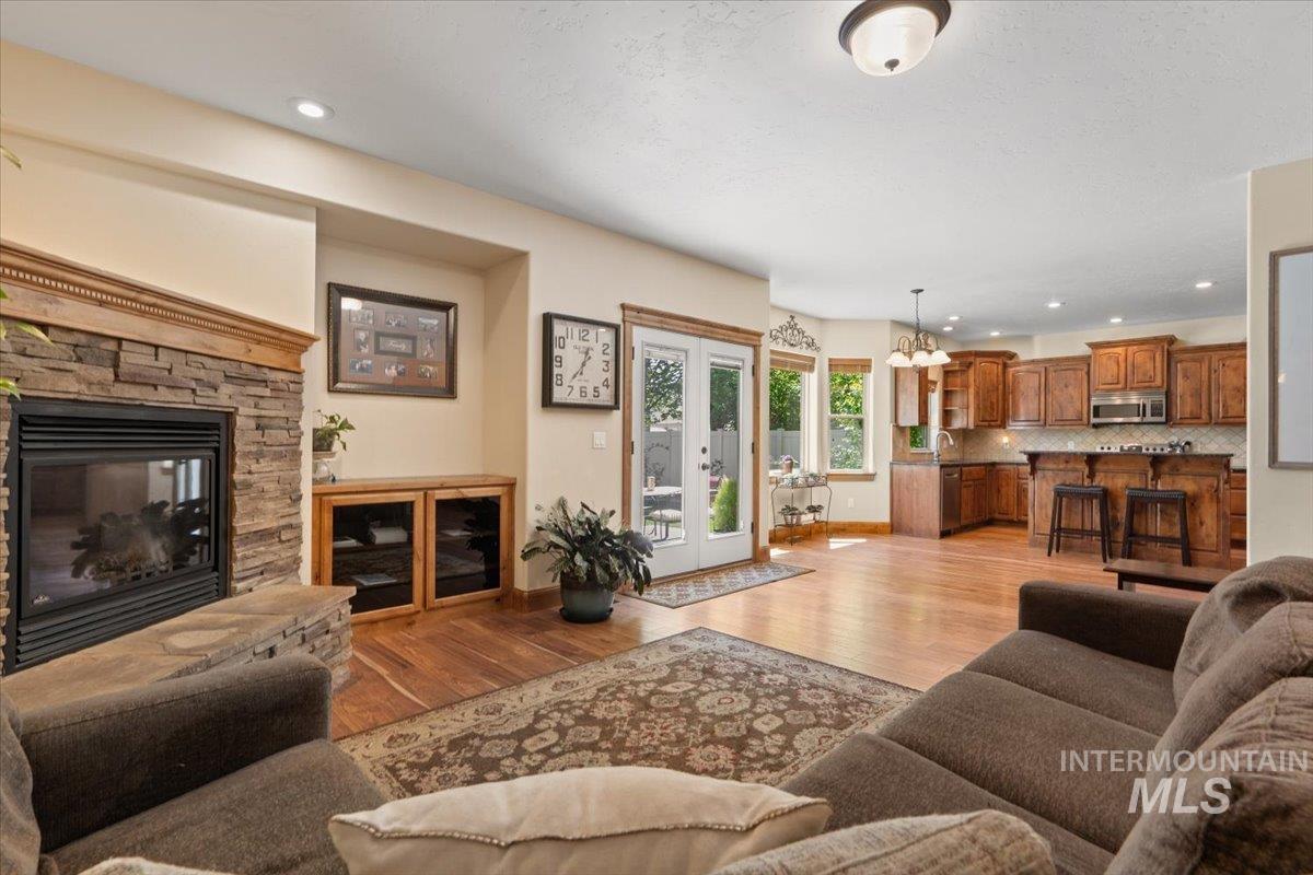 4154 North Tipton Avenue Meridian, ID 83646 - Photo 8 of 50 Spacious living area featuring hardwood flooring, a stacked stone fireplace with a wood mantel, recessed lighting, and built-in cabinetry